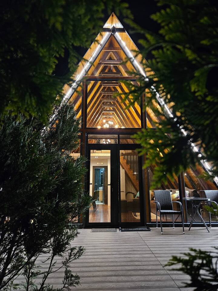 A-frame cabin with illuminated canopy walkway at night