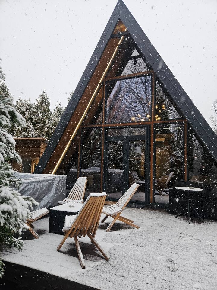A-frame cabin front covered in heavy winter snow